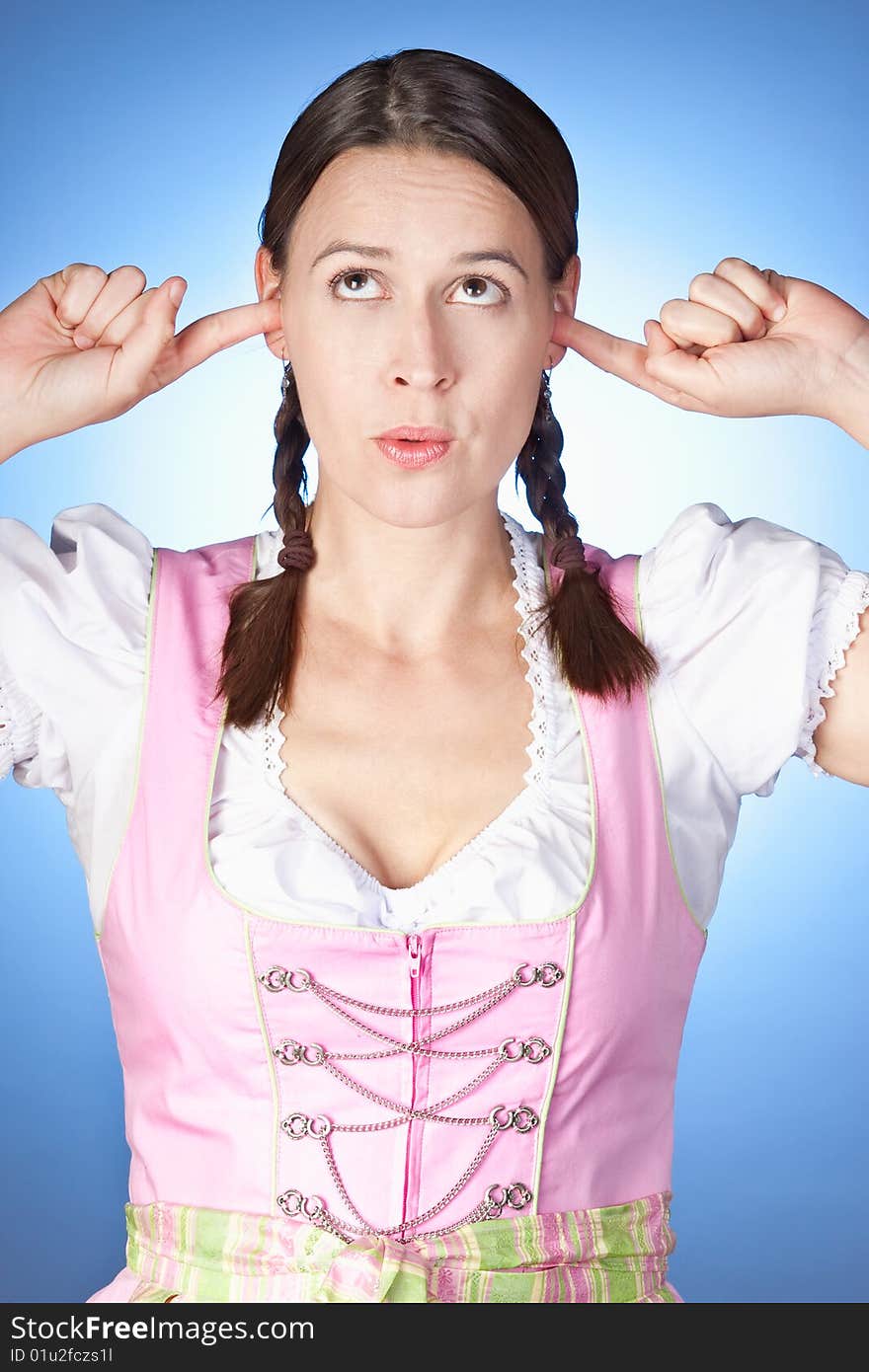 A woman in a dirndl with her fingers in her ears. A woman in a dirndl with her fingers in her ears