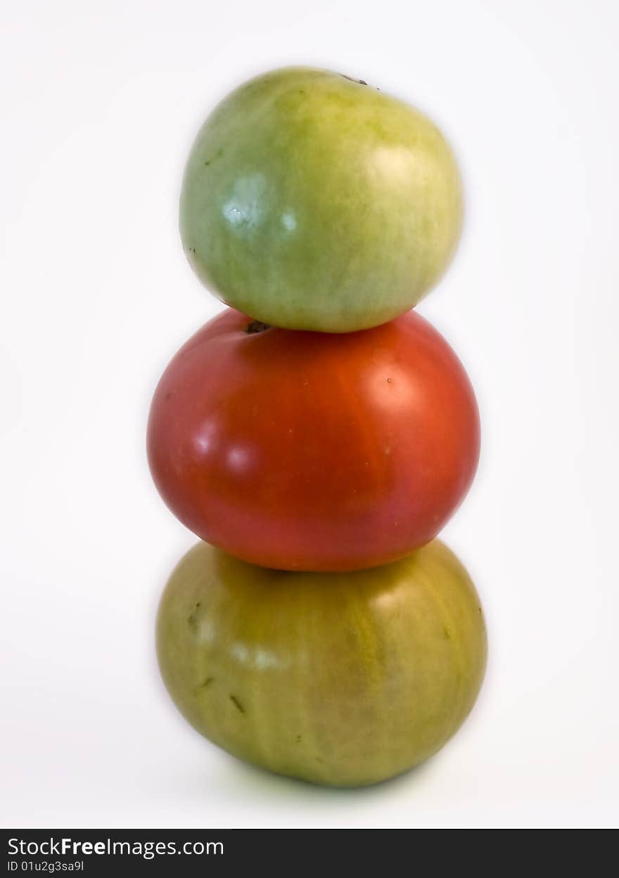 Three tomatoes, two green and one red, piled to form a totem. Three tomatoes, two green and one red, piled to form a totem.