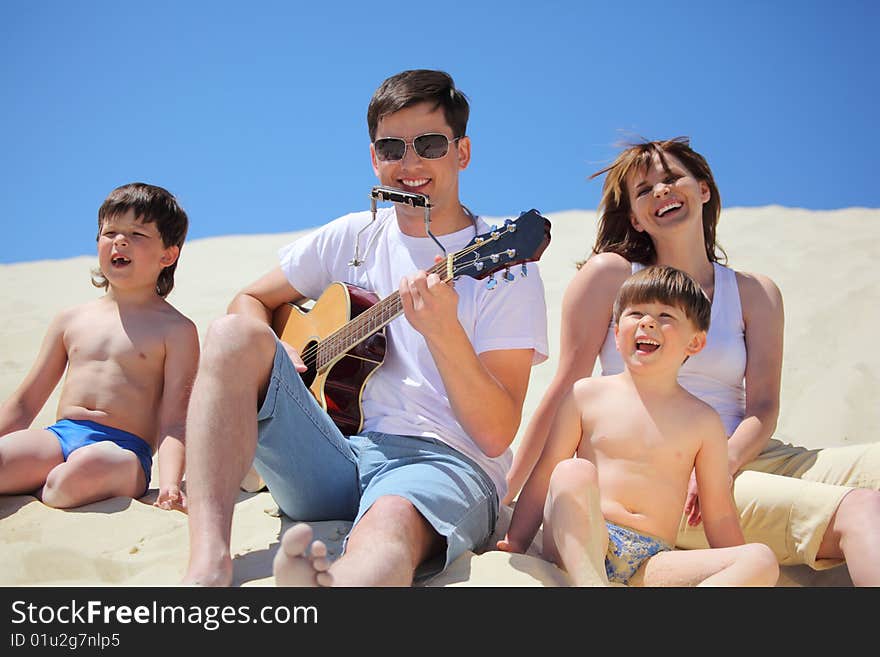 Guy plays guitar and lip accordion with children