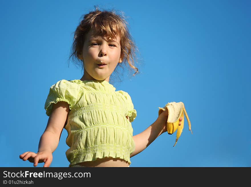 Girl eats banana against blue sky