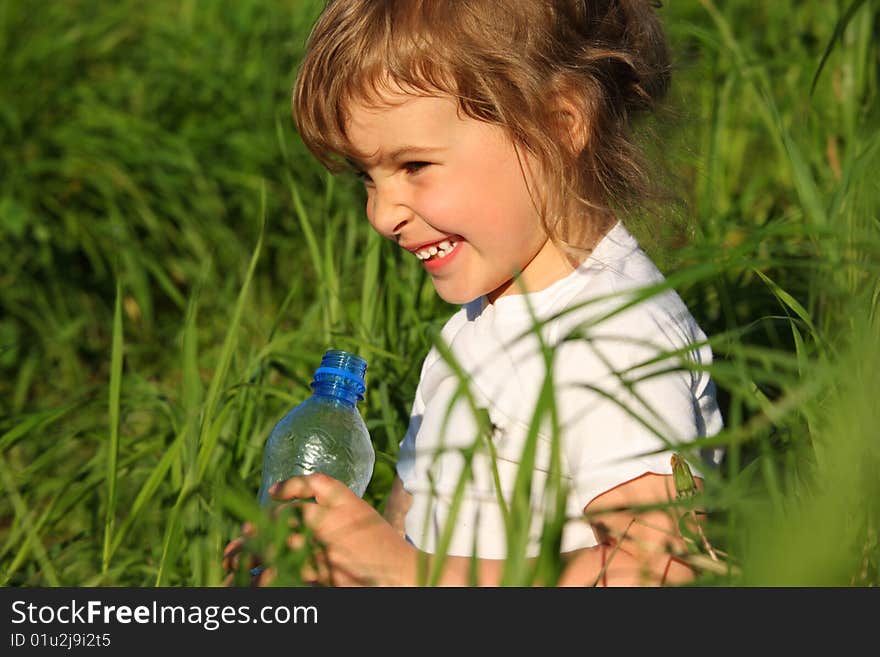 Smiling girl in grass with plastic bottle