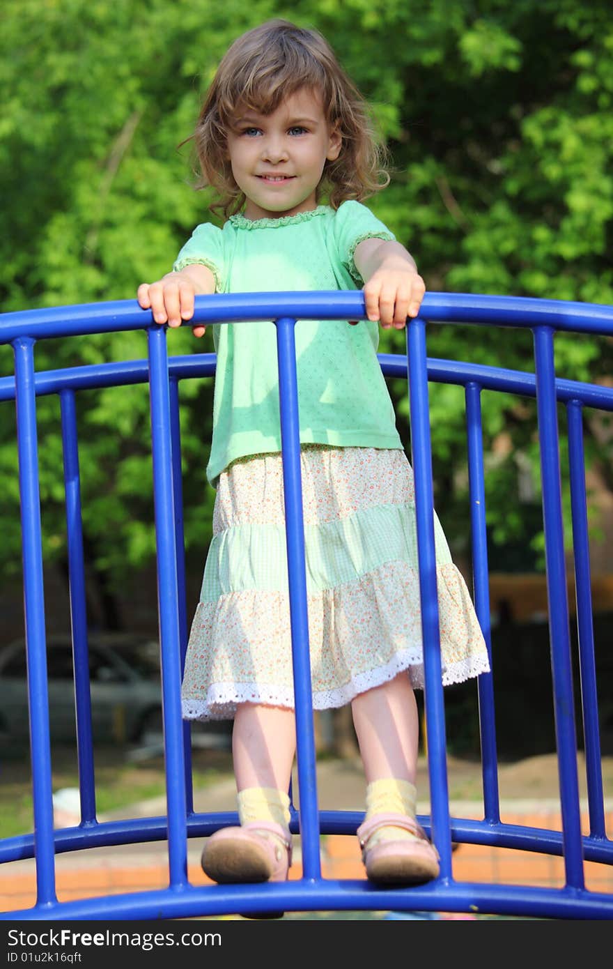 Little girl stands on bridge on playground