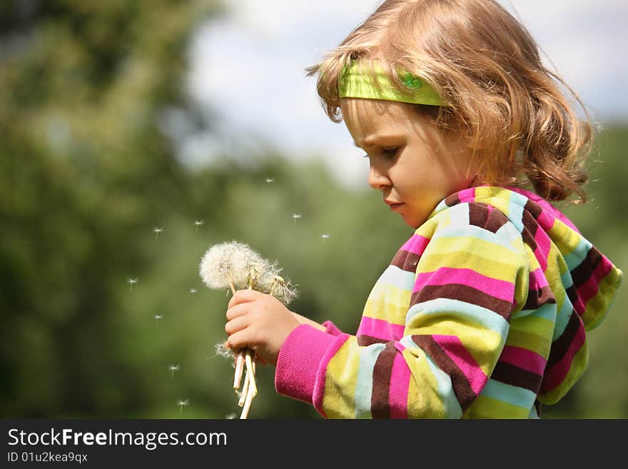 Thoughtful girl with dandelions in hand