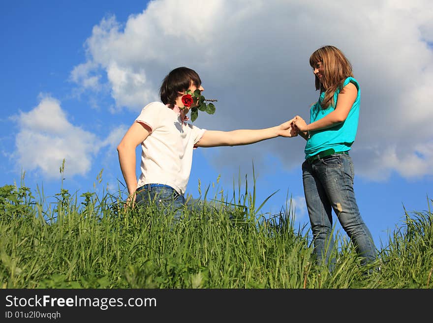 Guy with rose in mouth and girl in grass