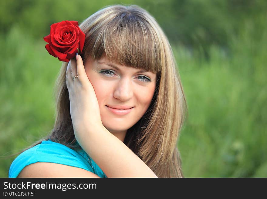 Smiling girl with red rose in hair