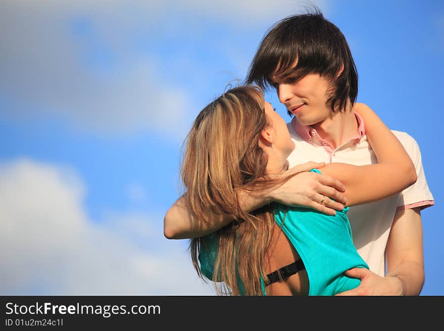 Young pair embraces against sky