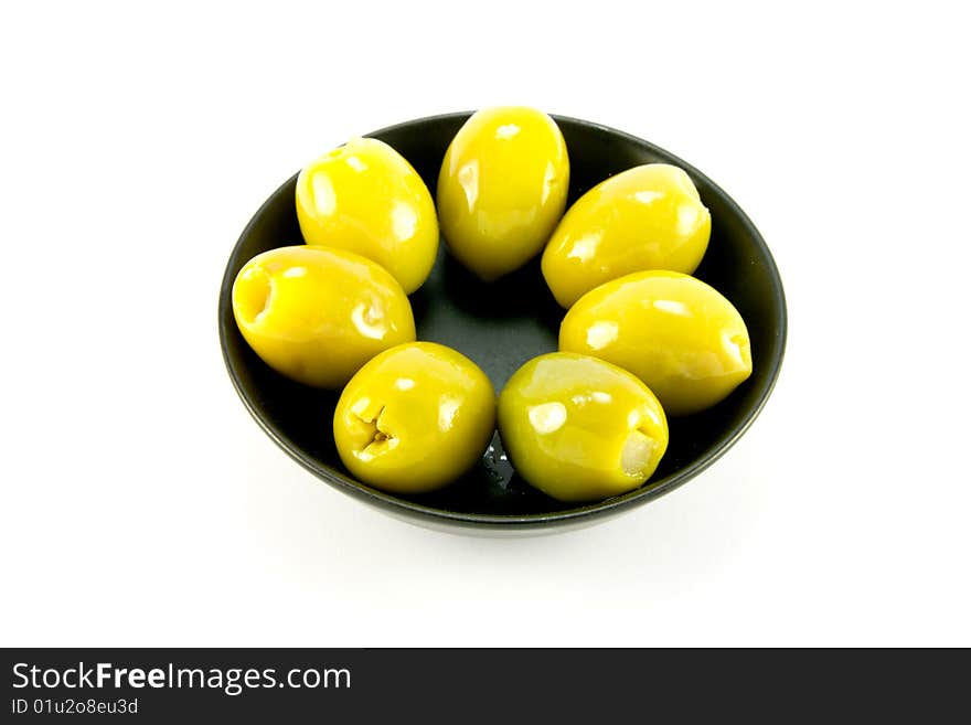 Green olives in a small round black bowl on a white background. Green olives in a small round black bowl on a white background