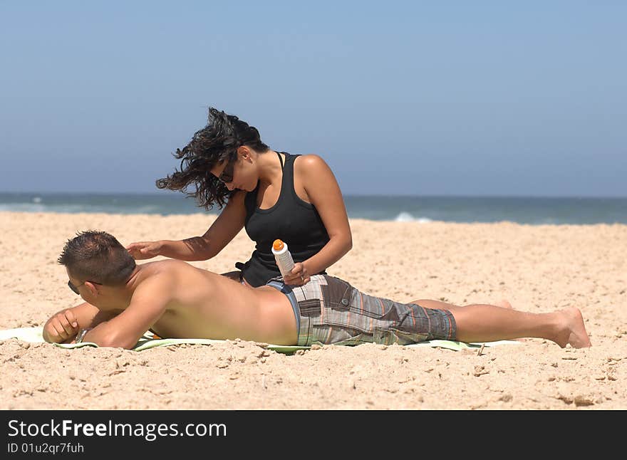 Lovely romantic couple applying suncream on the beach