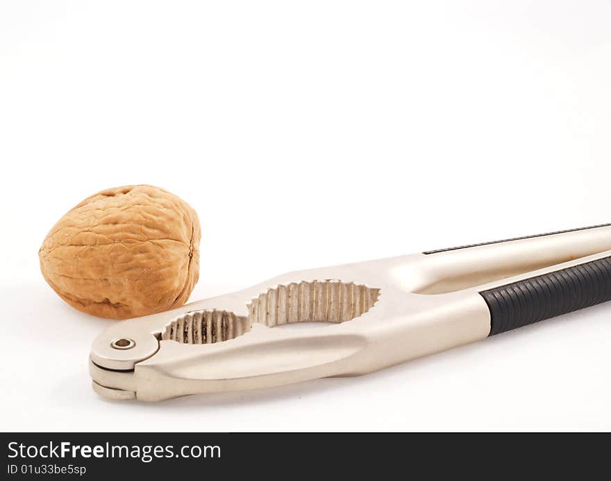 Walnut with a metal nutcracker over a white background. Walnut with a metal nutcracker over a white background.