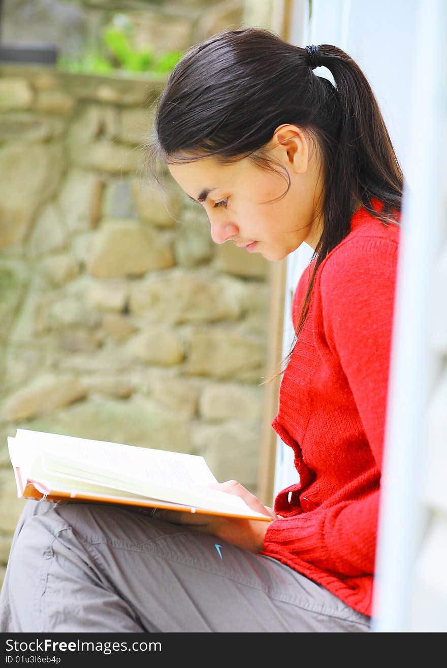 Young woman reading a book outdoors. Young woman reading a book outdoors.