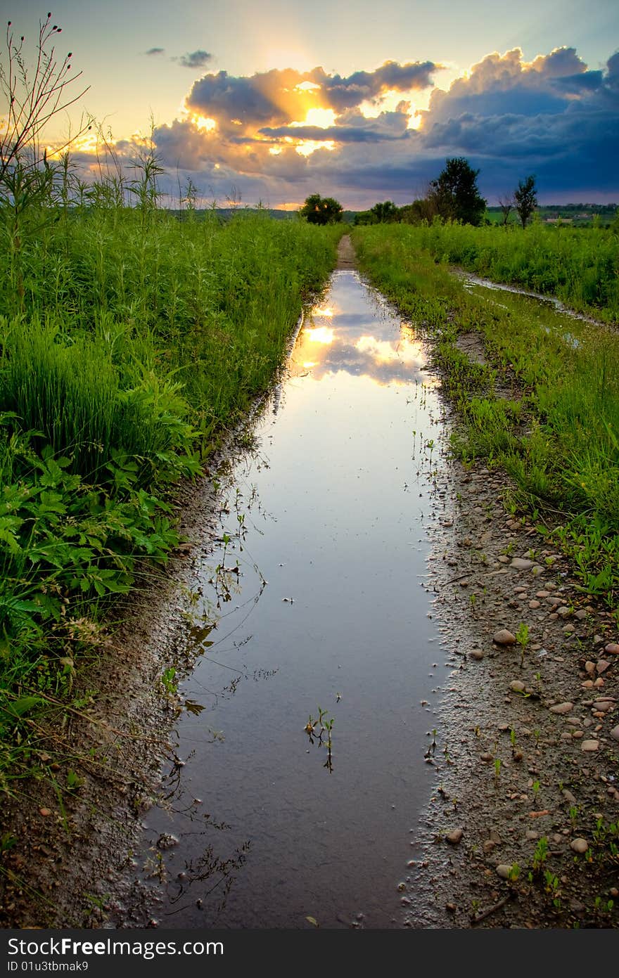 Pool on countryside road under sunset