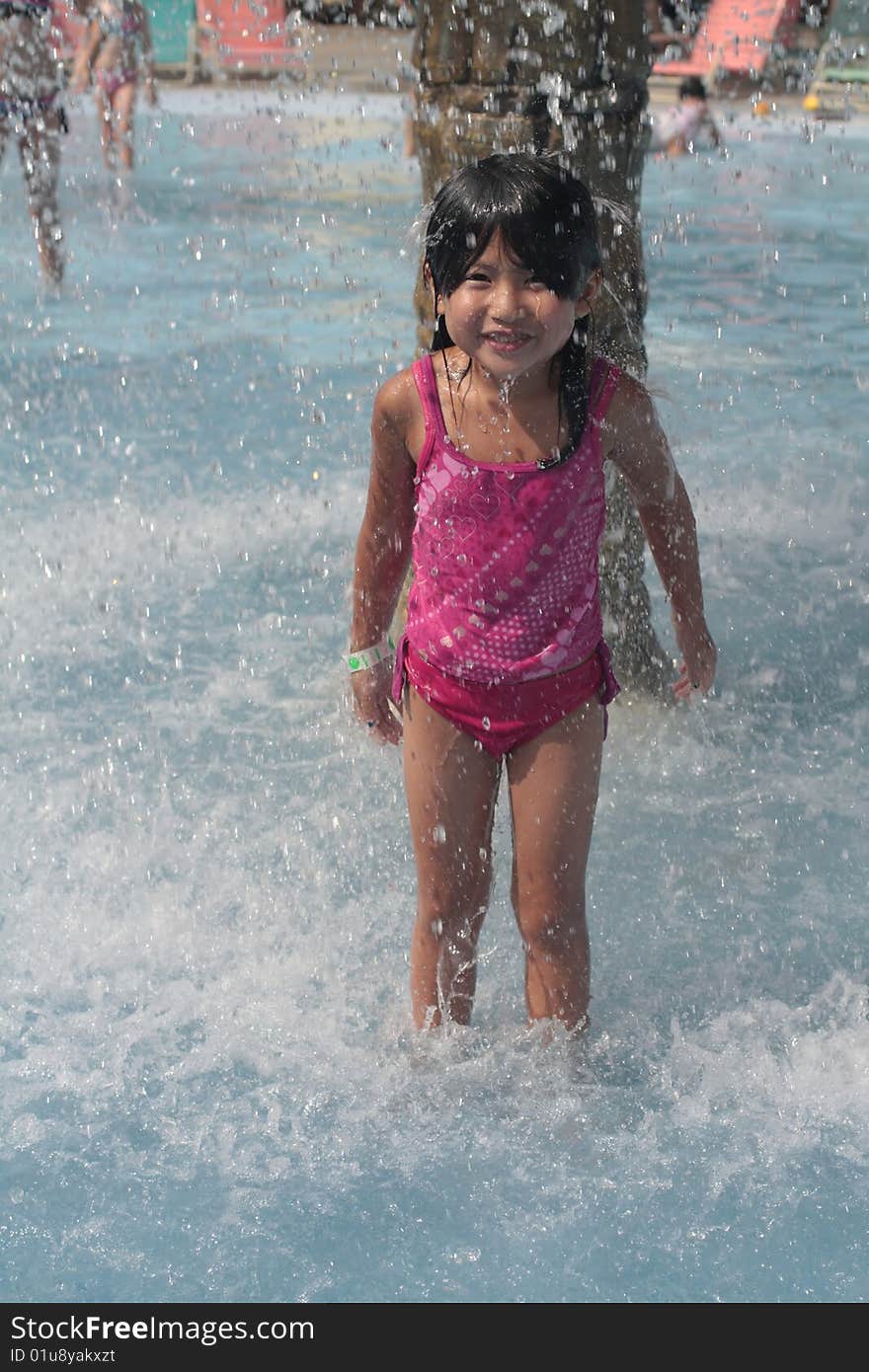 Cute young Asian child playing in splashing water. Cute young Asian child playing in splashing water.