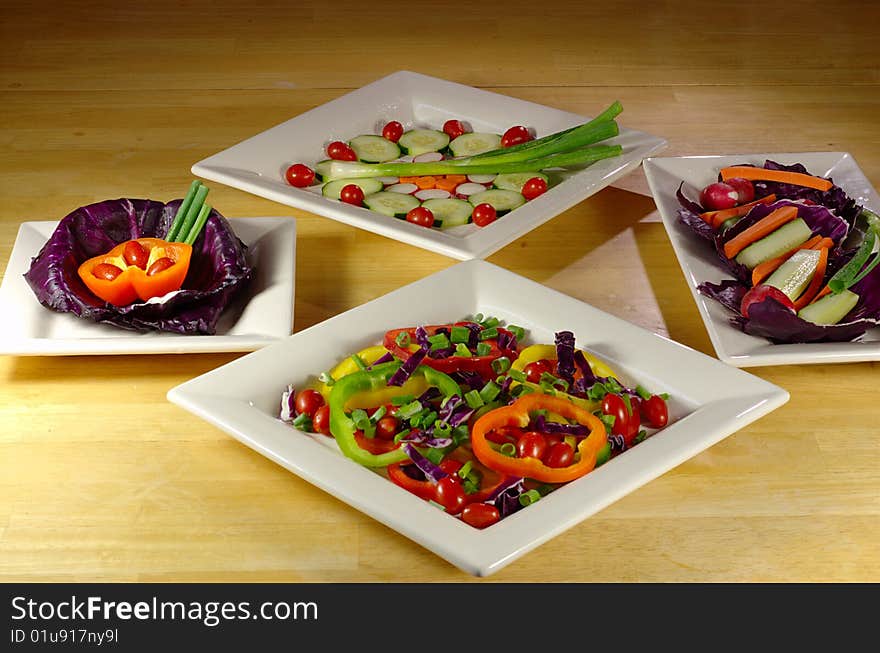 Many colorful vegetable plates arranged on wooden table.