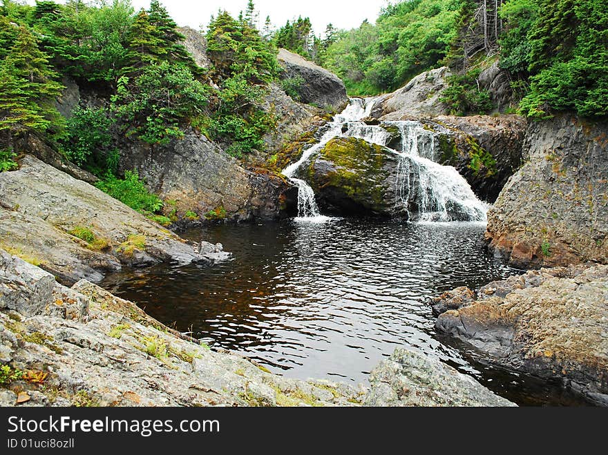 Scenic view of Flatrock river and waterfall with forest in background, Newfoundland, Canada. Scenic view of Flatrock river and waterfall with forest in background, Newfoundland, Canada.