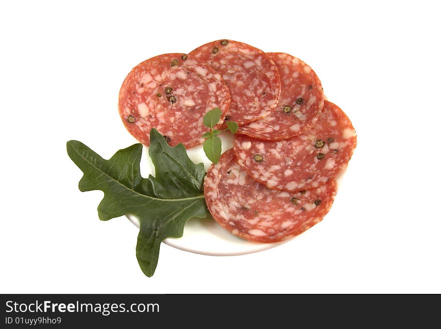 Salami sliced with salad on a white plate