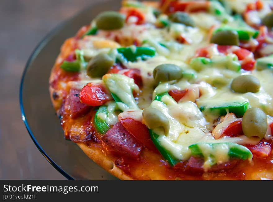 Closeup pizza with salami, tomatoes, green pepper, olives and cheese