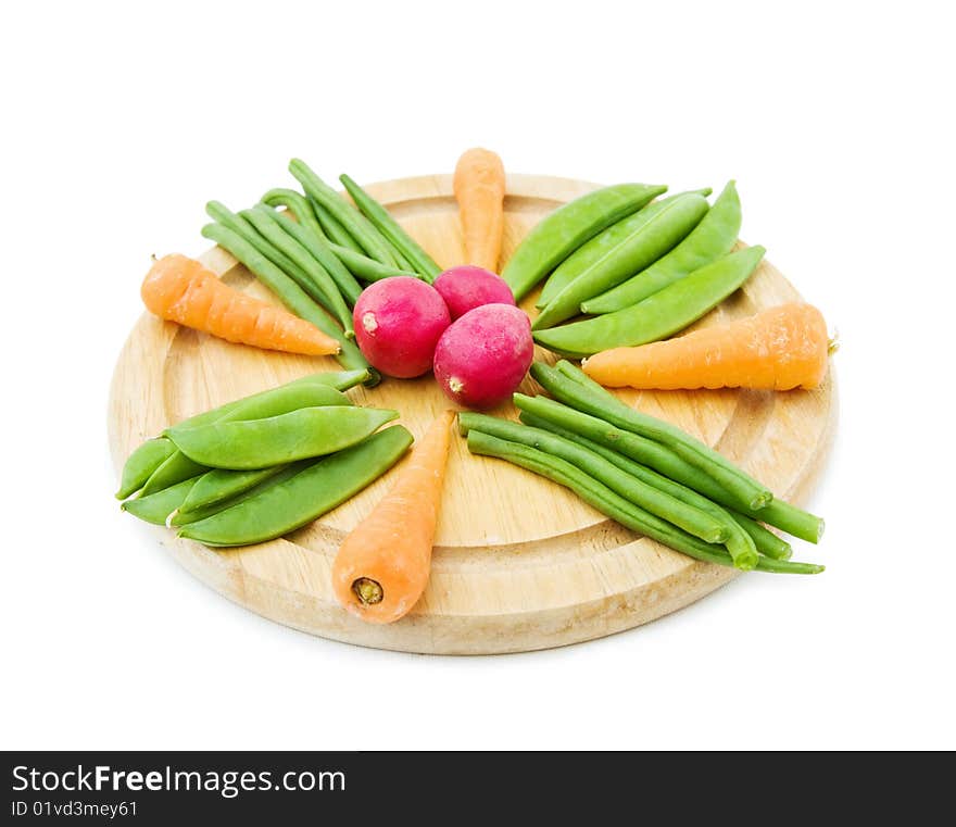 Healthy eating - mix of fresh baby vegetables on a round chopping board. Isolated on white. Healthy eating - mix of fresh baby vegetables on a round chopping board. Isolated on white.