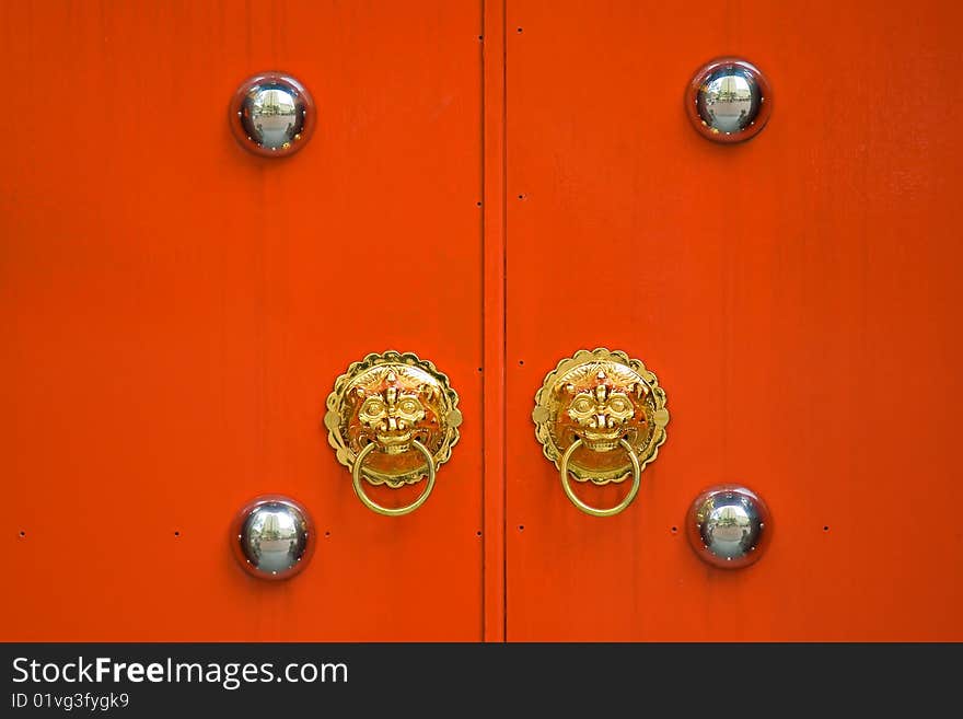 Red chinese door with a lion head door knocker at the entrance of old temple in city center. Red chinese door with a lion head door knocker at the entrance of old temple in city center