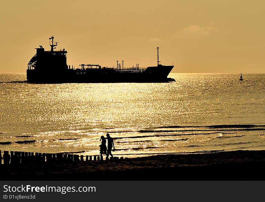 During sunset a ship passes the Dutch coast.