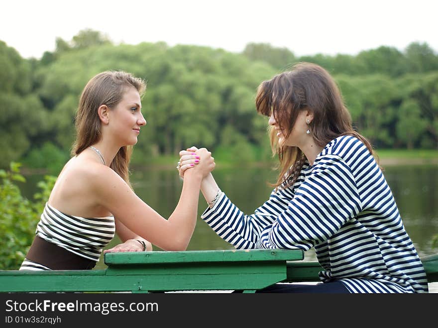 Two girls doing arm-wrestling outdoors. Two girls doing arm-wrestling outdoors