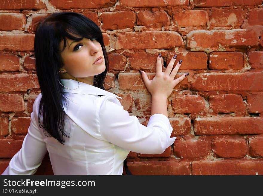 Beautiful girl stands near the brick wall. Beautiful girl stands near the brick wall