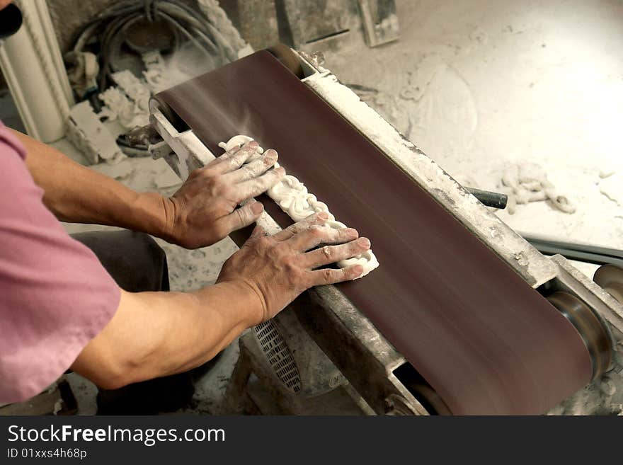 In workshop,a man use smoothing machine to make a lace border for construction deco material market. In workshop,a man use smoothing machine to make a lace border for construction deco material market.