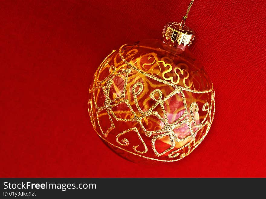 A close up of a glass gold painted bauble against red background. A close up of a glass gold painted bauble against red background