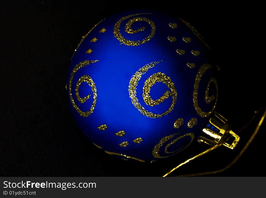 A close-up of a blue and gold christmas decoration against black. A close-up of a blue and gold christmas decoration against black