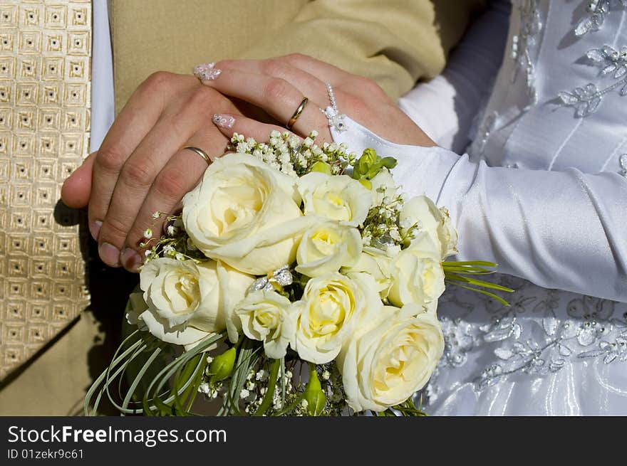 Bridal bouquet in the hands of the bride and groom after the marriage, the girl and the guy got married, they became husband and wife, creating a new family, accept the congratulations from parents and friends. Bridal bouquet in the hands of the bride and groom after the marriage, the girl and the guy got married, they became husband and wife, creating a new family, accept the congratulations from parents and friends