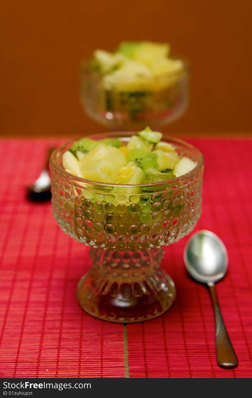 Two ice-cream bowls with fruit salad and spoons. Two ice-cream bowls with fruit salad and spoons