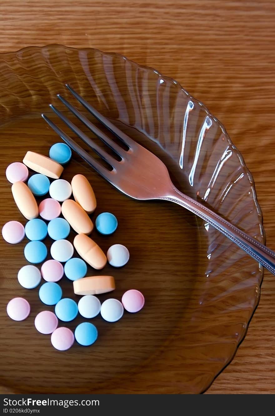 Plate with coloured vitamins and a fork on it. Plate with coloured vitamins and a fork on it