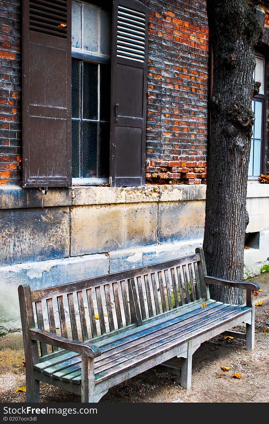 A solitary wooden bench rests next to an old building in Paris, France