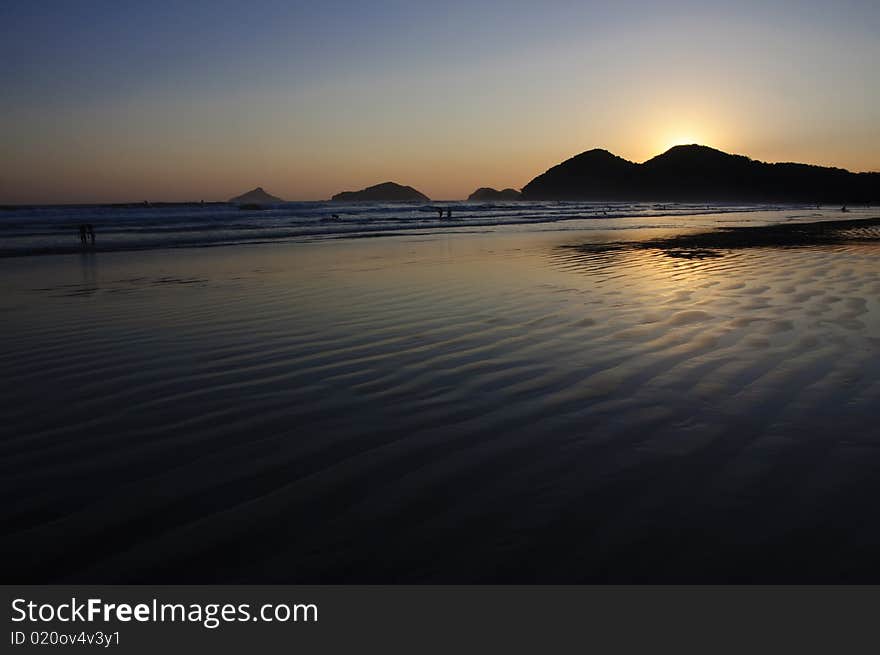 Sunset at the Baleia Beach in Brazil, with golden reflexion from the sun in the ocean and people enjoying the end of the afternoon. Sunset at the Baleia Beach in Brazil, with golden reflexion from the sun in the ocean and people enjoying the end of the afternoon