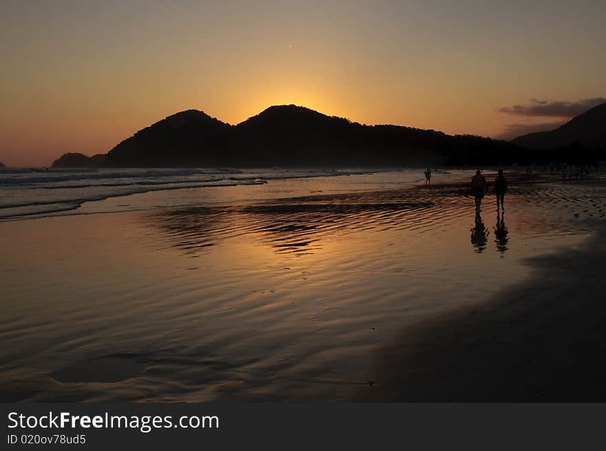 Sunset at the Baleia Beach in Brazil, with golden reflexion from the sun in the ocean and people enjoying the end of the afternoon. Sunset at the Baleia Beach in Brazil, with golden reflexion from the sun in the ocean and people enjoying the end of the afternoon