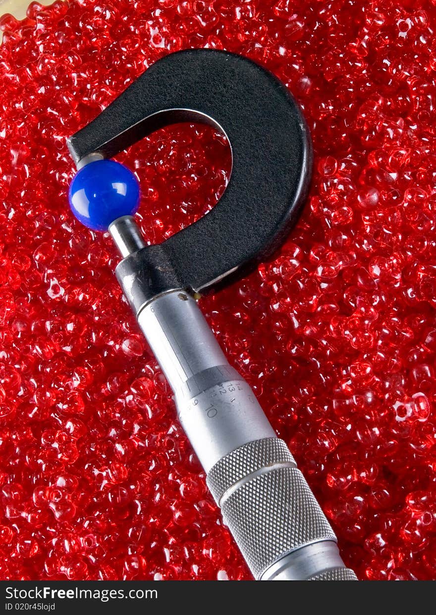 Micrometer with Beads and Balls. Plastic colorful beads and a micrometer measuring a plastic ball