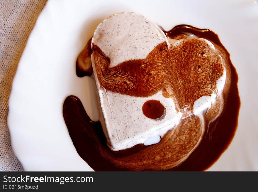 Ice-cream heart with chocolate sauce on a white plate