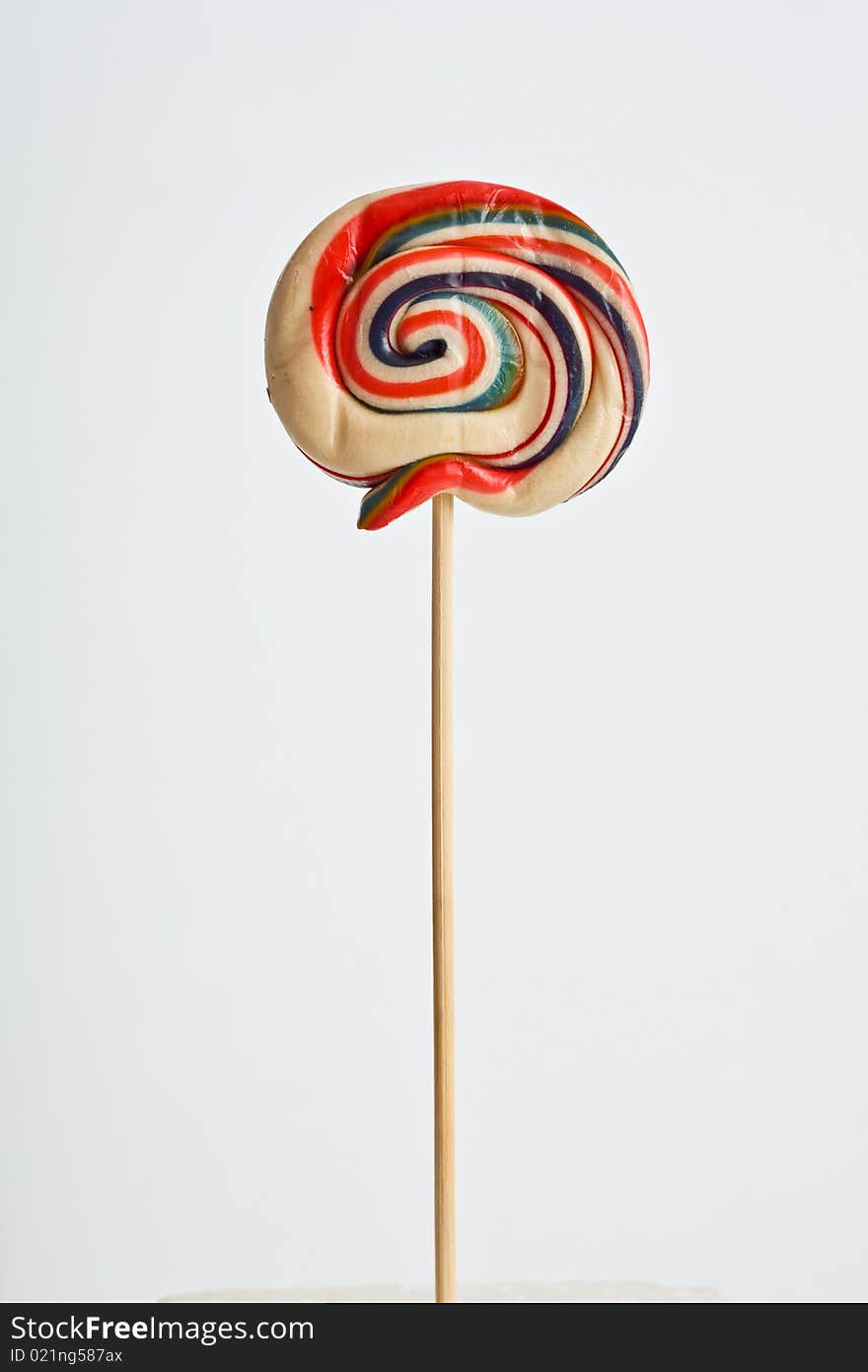 A colorful lollipop on white background supported on a polystyrene white cube. A colorful lollipop on white background supported on a polystyrene white cube