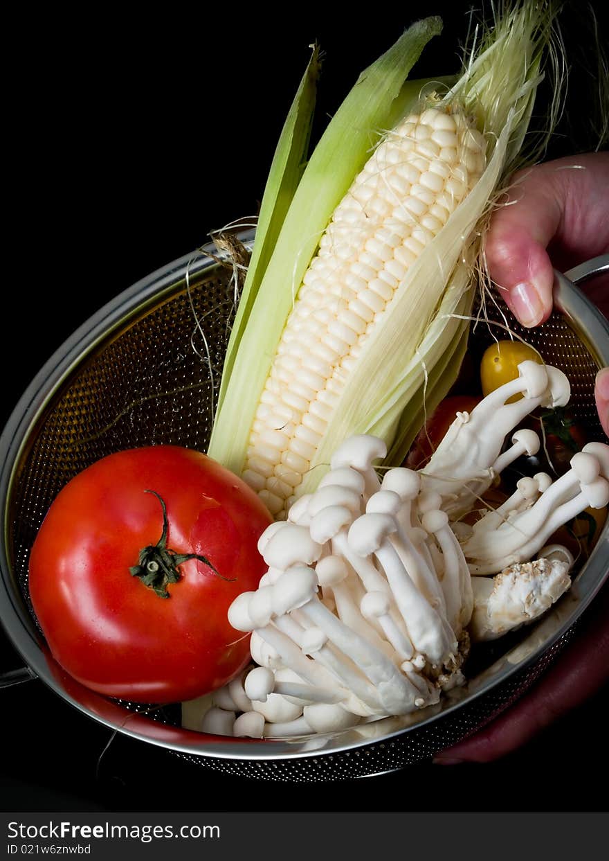 Mix of vegetables on black in  colander