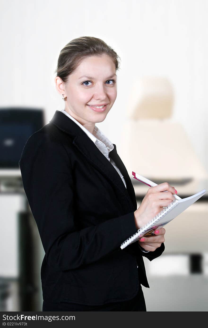 Young businesswoman does records by pen in notepad. Young businesswoman does records by pen in notepad