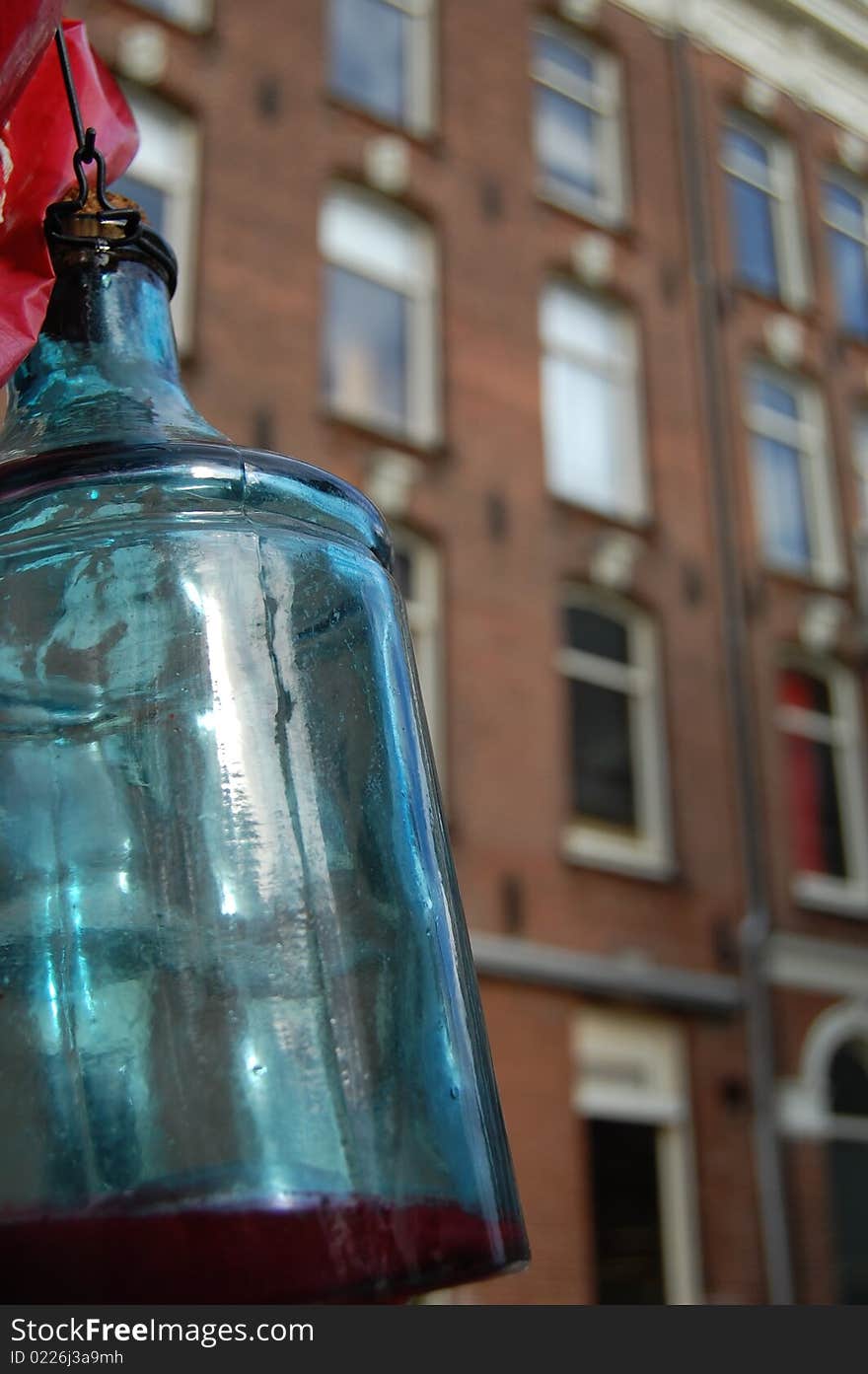 A bottle hanging in Amsterdam with canal  houses in The back