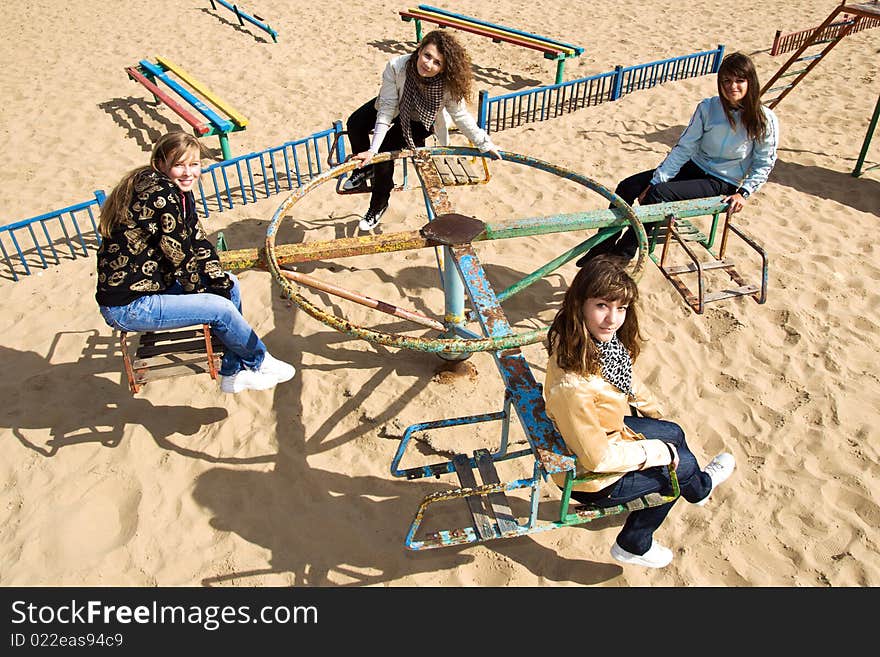 Four cute teenage girls riding merry-go-round. Four cute teenage girls riding merry-go-round