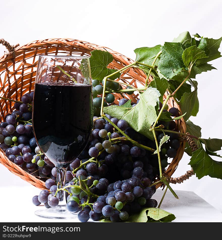 Ripe harvested Grapes in a basket with a glass of wine