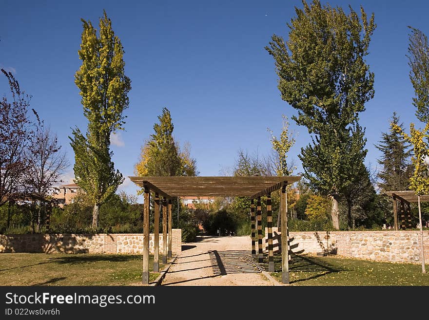 A light, wooden awning or covering over a walkway in a park. A light, wooden awning or covering over a walkway in a park.