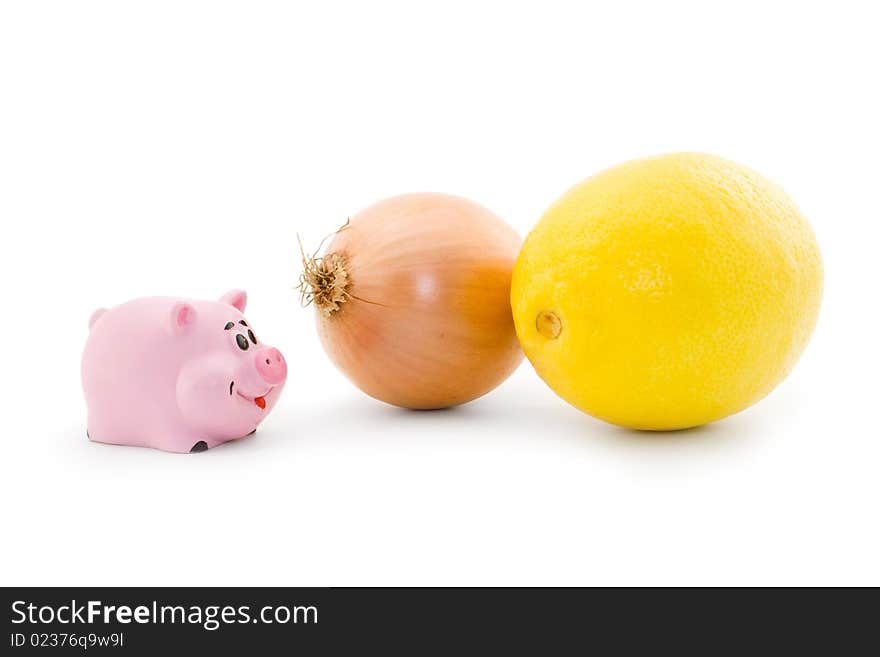 Small pink piggy looks at onion and lemon. Small pink piggy looks at onion and lemon