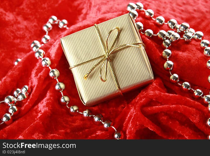 Small golden festive box on red velvet background