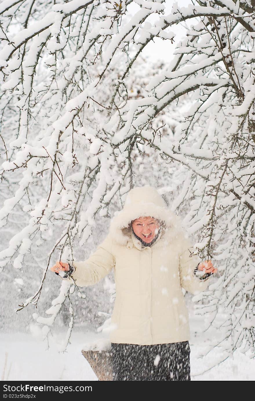 Young woman shaking the snowy tree and laughing. With some motion blur. Young woman shaking the snowy tree and laughing. With some motion blur.