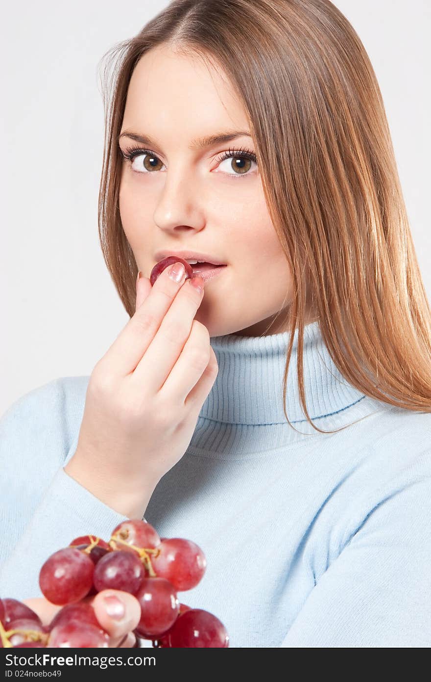 Young woman eating red grape from her hand. Young woman eating red grape from her hand