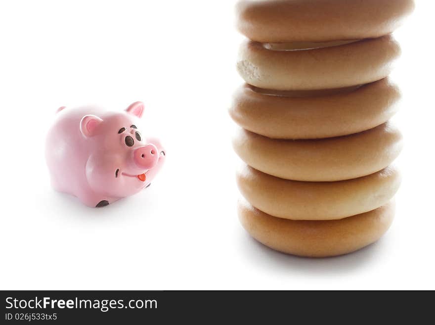 Toy pig looking at a pile of bagels. Unhealthy diet. Toy pig looking at a pile of bagels. Unhealthy diet.