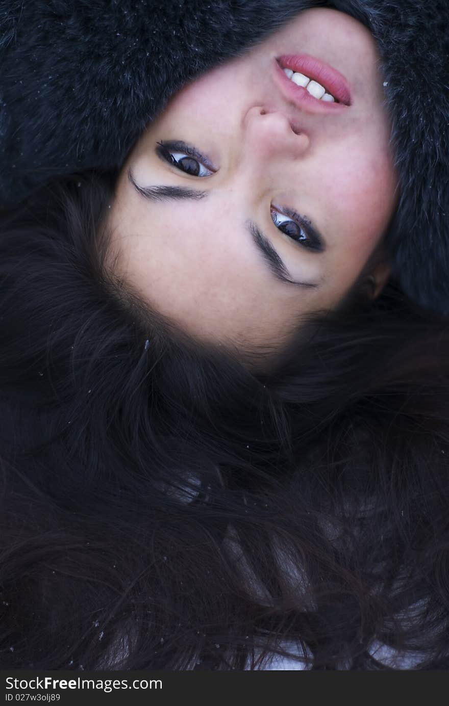 Face portrait of young attractive brunette woman lying on the snow. Perfect hair texture. Outdoor winter photo. Face portrait of young attractive brunette woman lying on the snow. Perfect hair texture. Outdoor winter photo.