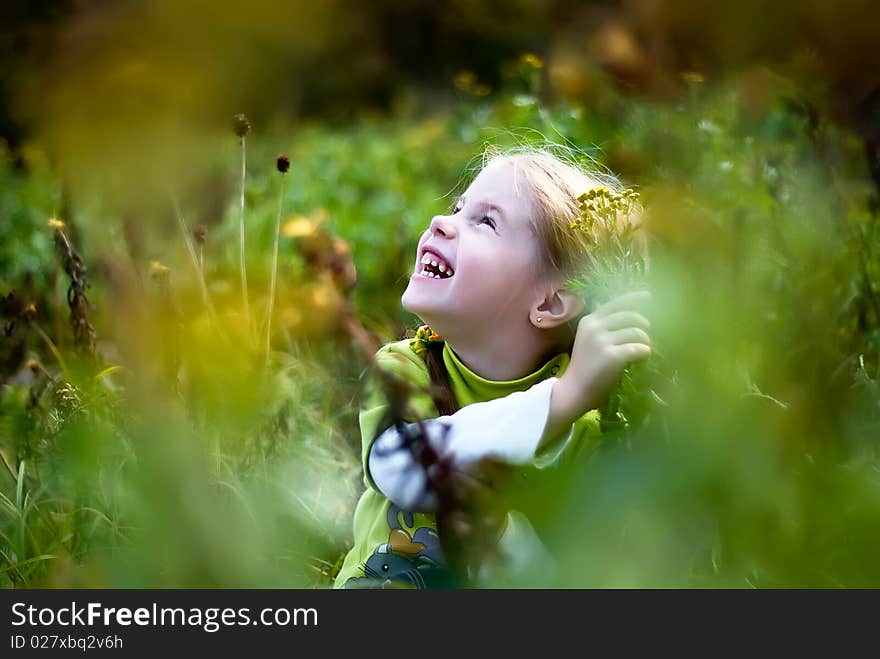 Laughing little girl in the meadow through the grass. Laughing little girl in the meadow through the grass